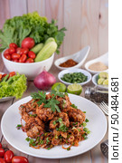 Spicy minced chicken on a white plate complete with cucumber, lettuce and side dishes on wooden table. Стоковое фото, агентство Ingram Publishing / Фотобанк Лори