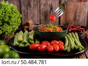 Sweet pork in a black bowl, complete with cucumbers, long beans, tomatoes, and side dishes. Selective focus. Стоковое фото, агентство Ingram Publishing / Фотобанк Лори