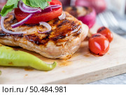 Chicken steak placed on a wooden tray with bell peppers, tomatoes, red onions, pineapple sauce, lettuce, and sesame seeds. Стоковое фото, агентство Ingram Publishing / Фотобанк Лори
