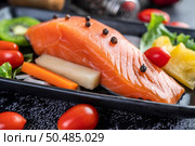 Raw salmon fillets, pepper, kiwi, pineapples, and rosemary onto a plate and black cement floor. Стоковое фото, агентство Ingram Publishing / Фотобанк Лори