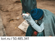Man sitting beggar with a cup and money. Selective focus. Стоковое фото, агентство Ingram Publishing / Фотобанк Лори