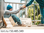 The man sitting begging on an overpass with messages homeless people please help and work well with food. Стоковое фото, агентство Ingram Publishing / Фотобанк Лори