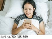 Young women wearing striped shirts playing smart phones. Selective focus. Стоковое фото, агентство Ingram Publishing / Фотобанк Лори