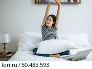 That woman sat on the bed, raised her hand, and placed the laptop. Стоковое фото, агентство Ingram Publishing / Фотобанк Лори