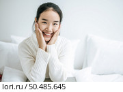 The woman sat on the bed, held the cheek, and smiled happily. Стоковое фото, агентство Ingram Publishing / Фотобанк Лори