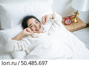 Woman wearing a white shirt lying on the bed, white pillow ready to wake up. Стоковое фото, агентство Ingram Publishing / Фотобанк Лори
