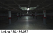 Shadowy underground parking garage with flickering fluorescent lights illuminating grey concrete columns, generating mysterious industrial ambiance through architectural perspective. Стоковое видео, видеограф Данил Руденко / Фотобанк Лори