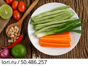 Thai style spicy food, Som Tum food concept, props decoration Garlic, lemon, tomatoes, chili, long-hatched beans, spring onions, shallots,  and carrots and peanuts on wood spoon on wood table. Стоковое фото, агентство Ingram Publishing / Фотобанк Лори