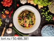 Stir Fried Spicy Chicken in white plate with spices on black cement. Стоковое фото, агентство Ingram Publishing / Фотобанк Лори
