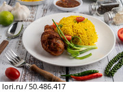 Chicken Biryani in a plate with spices on a white wooden floor. Стоковое фото, агентство Ingram Publishing / Фотобанк Лори