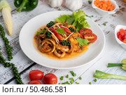 Squid fried with curry paste in white plate, with vegetables and side dishes on a white wooden floor. Selective focus. Стоковое фото, агентство Ingram Publishing / Фотобанк Лори