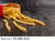 French fries poured out of a bag on a black cement floor. Стоковое фото, агентство Ingram Publishing / Фотобанк Лори