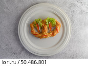 Freshly baked soft pretzel with generous sprinkling of coarse salt and sesame on white dish, decorate with lettuce and carrot beautifully, copy space. Стоковое фото, агентство Ingram Publishing / Фотобанк Лори