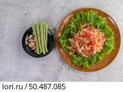 Thai papaya salad on salad in a wooden plate with Yardlong beans and garlic, Top view. Стоковое фото, агентство Ingram Publishing / Фотобанк Лори