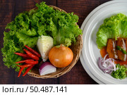 Top View Ingredient herb for cooking salad put in a wicker basket and sardine with tomato sauce arranged nicely in white dish placed on wooden table, copy space. Стоковое фото, агентство Ingram Publishing / Фотобанк Лори