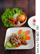Mixed sardine salad was beautiful arrangement in white plate, stainless spoon and fork on napkin, blurred sardine with tomato sauce and cooking ingredient in weave basket placed nearly on wooden table. Стоковое фото, агентство Ingram Publishing / Фотобанк Лори