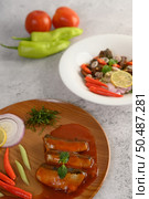 Vertical image, selective focus the sardine in tomato sauce on wooden tray, blurred spicy Canned Sardine Salad with herb ingredient in white dish, copy space. Стоковое фото, агентство Ingram Publishing / Фотобанк Лори