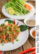 Spicy Minced Pork Salad on a white plate with red onion, lemon grass, garlic, yardlong beans, kaffir lime leaves, and spring onion. Стоковое фото, агентство Ingram Publishing / Фотобанк Лори