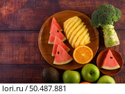 Watermelon, pineapple, oranges, cut into pieces with avocado, Broccoli and apples on wood table. Top view. Стоковое фото, агентство Ingram Publishing / Фотобанк Лори
