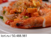 Stir-fried prawns with glass noodles in a white plate placed on a cloth with eggs and garlic. Стоковое фото, агентство Ingram Publishing / Фотобанк Лори