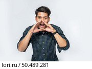 A man wore a white shirt and black trousers and make a hand shout of joy. Стоковое фото, агентство Ingram Publishing / Фотобанк Лори