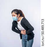 A woman standing with a stomach ache and presses her hand on her stomach. Стоковое фото, агентство Ingram Publishing / Фотобанк Лори