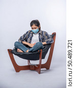 A woman sitting in a chair with abdominal pain and pressing her hand on her stomach. Стоковое фото, агентство Ingram Publishing / Фотобанк Лори