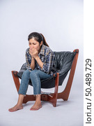 A woman who is uncomfortable and sits on a chair. Стоковое фото, агентство Ingram Publishing / Фотобанк Лори