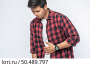 A man stands with a stomachache and puts his hand on his stomach. Стоковое фото, агентство Ingram Publishing / Фотобанк Лори