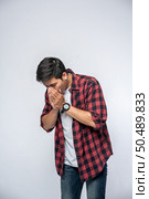 A man coughing and covering her mouth with her hand. Стоковое фото, агентство Ingram Publishing / Фотобанк Лори