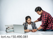 Men teach women how to work with laptops at work. Стоковое фото, агентство Ingram Publishing / Фотобанк Лори