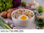 Boiled egg porridge in a white cup and sprinkled with sliced ??spring onions. Стоковое фото, агентство Ingram Publishing / Фотобанк Лори