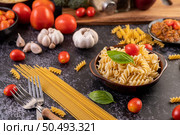Macaroni sauteed with tomatoes and basil on a gray plate. Стоковое фото, агентство Ingram Publishing / Фотобанк Лори