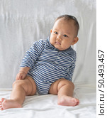 A baby learns to sit on a white bed. Стоковое фото, агентство Ingram Publishing / Фотобанк Лори
