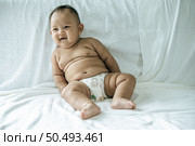 A baby learns to sit on a white bed. Стоковое фото, агентство Ingram Publishing / Фотобанк Лори