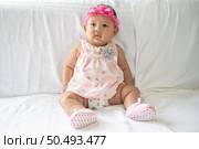 A baby learns to sit on a white bed. Стоковое фото, агентство Ingram Publishing / Фотобанк Лори