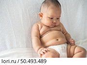A baby learns to sit on a white bed. Стоковое фото, агентство Ingram Publishing / Фотобанк Лори
