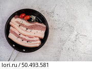 Pork belly in a pan with pepper seeds Tomatoes and spices. Selective focus. Стоковое фото, агентство Ingram Publishing / Фотобанк Лори