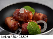 Sausage wrapped in pork belly in a pan with sesame and mint. Selective focus. Стоковое фото, агентство Ingram Publishing / Фотобанк Лори