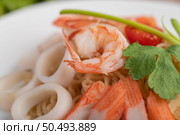 Stir-fried instant noodle with prawn and crab stick along with tomatoes and peppers in a white plate on a wooden floor. Стоковое фото, агентство Ingram Publishing / Фотобанк Лори
