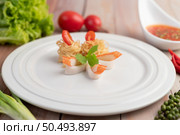 Stir-fried instant noodle with prawn and crab stick along with tomatoes and peppers in a white plate on a wooden floor. Стоковое фото, агентство Ingram Publishing / Фотобанк Лори