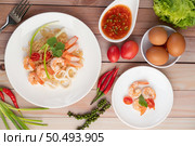 Stir-fried instant noodle with prawn and crab stick along with tomatoes and peppers in a white plate on a wooden floor. Стоковое фото, агентство Ingram Publishing / Фотобанк Лори