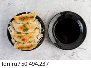 Gyoza in a black cup with a cup of sauce. Стоковое фото, агентство Ingram Publishing / Фотобанк Лори
