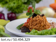 Stir-fried noodles with minced pork, edamame, tomatoes and mushrooms in a white plate. Стоковое фото, агентство Ingram Publishing / Фотобанк Лори