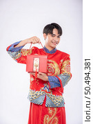 Man wear Cheongsam ready to give red bag to sister for surprising in traditional day. Стоковое фото, агентство Ingram Publishing / Фотобанк Лори