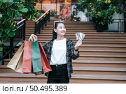 Portrait of young Asian woman in protection mask, eyeglasses on head standing with multi color shopping paper bag and show three credit cards in hand,  Lifestyle and shopping concept, copy space. Стоковое фото, агентство Ingram Publishing / Фотобанк Лори
