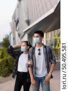 Asian Young Couple in protection mask standing outdoor of large building, They are discussion with happiness, New normal lifestyle amid coronavirus outbreak. Стоковое фото, агентство Ingram Publishing / Фотобанк Лори