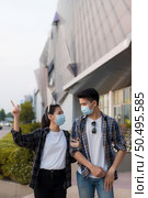 Asian Young Couple in protection mask standing outdoor of large building, They are discussion with happiness, New normal lifestyle amid coronavirus outbreak. Стоковое фото, агентство Ingram Publishing / Фотобанк Лори