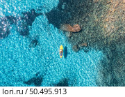 Aerial view of with man on sup board in blue sea at sunset in summer. Man on floating canoe in transparent azure water. Kayak. Sardinia island, Italy. Tropical seascape. Active travel. Drone view. Стоковое фото, агентство Ingram Publishing / Фотобанк Лори