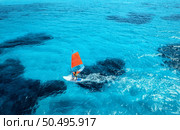 Aerial view of windsurfer on blue sea at sunny summer day. Windsurfing. Extreme sport and vacation. Top view of man on windsurfer board, waves, clear azure water in Sardinia, Italy. Tropical landscape. Стоковое фото, агентство Ingram Publishing / Фотобанк Лори